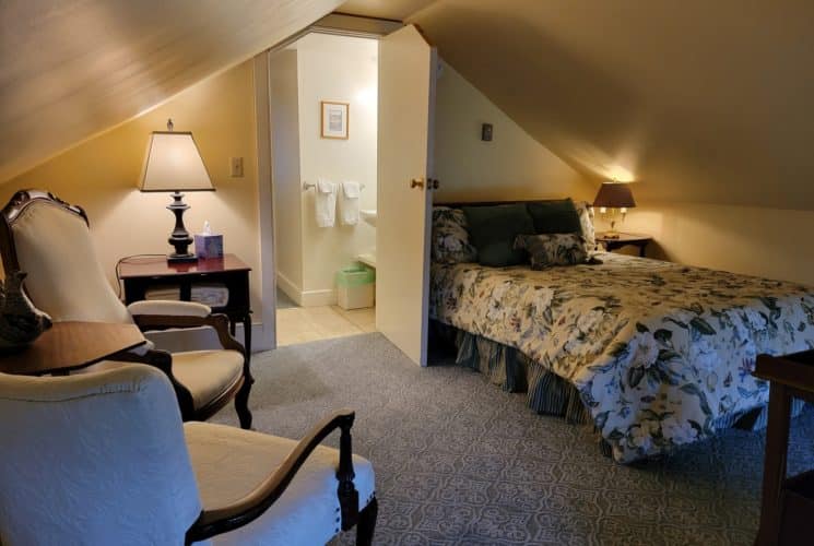 bedroom with two white chairs and full sized bed