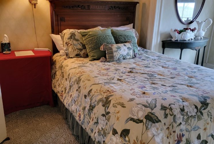 Bedroom with queen bed with floral comforter and window overlooking mountains