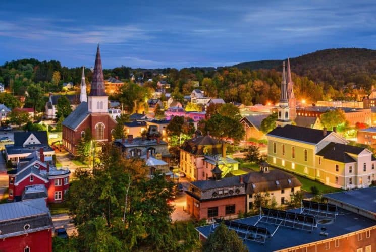 Beautiful overhead lit-up at night view of a lovely town including three church spires and antique buildings.