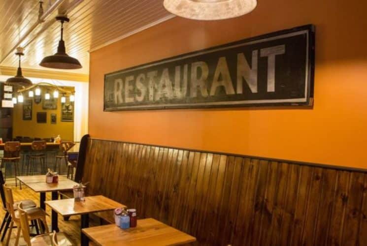 Long wooden bench seating in a restaurant with wooden floors and antique decor.