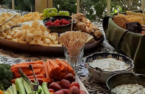 Snack table set up with cheese, crudite, dips and crackers.