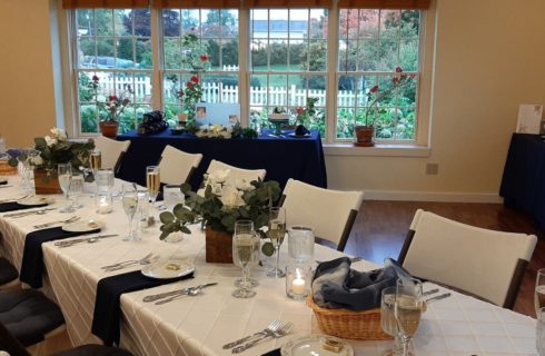 Reception table decorated elegantly in white and midnight blue with wooden boxes containing greenery and white flowers.