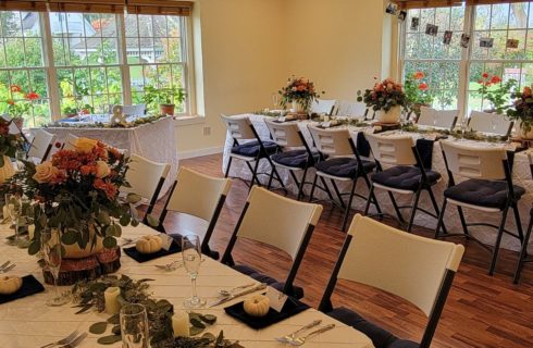 Bright and airy room with long tables decorated in white pumpkins and fall florals for an Autumn wedding receptions.
