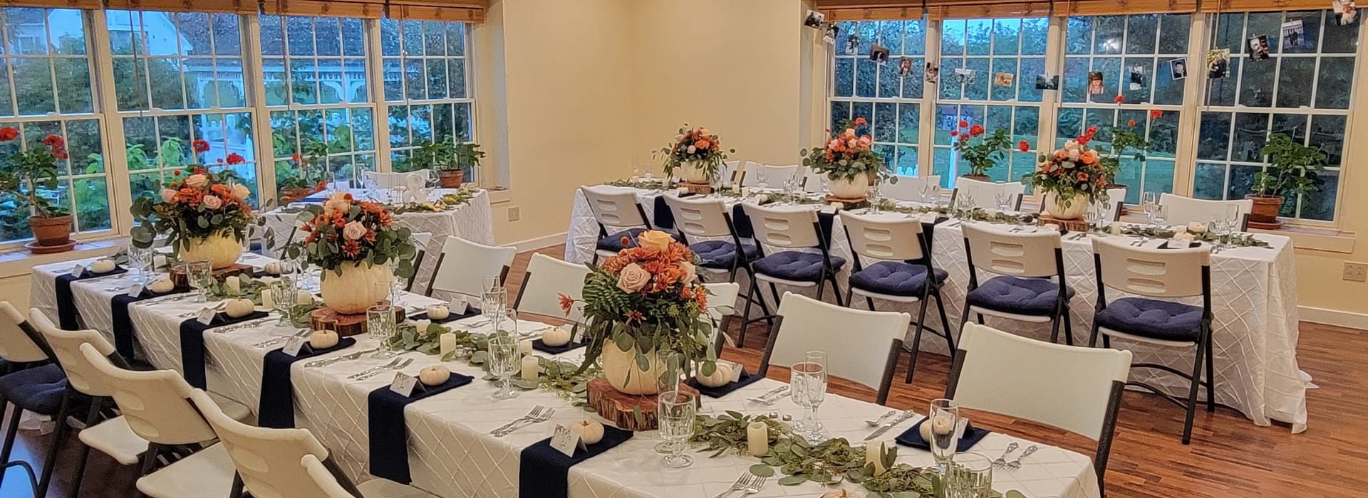 Bright and airy room with long tables decorated in white pumpkins and fall florals for an Autumn wedding receptions.