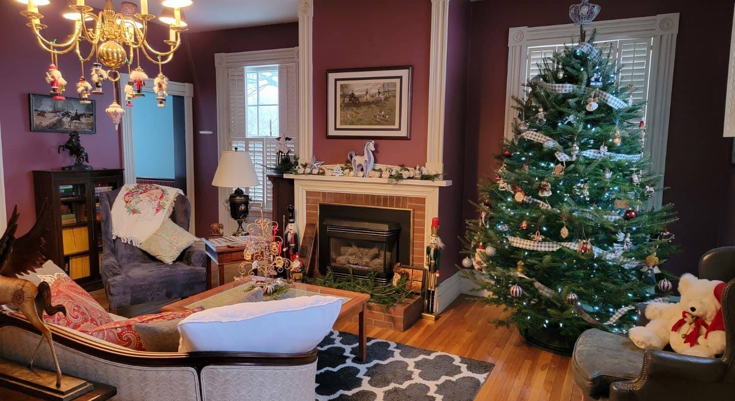 Living room with hardwood flooring, red walls, white trim, fireplace, and decorated Christmas tree